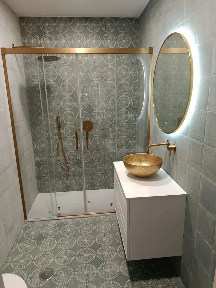 Baño con mampara de ducha, lavabo sobre mueble y grifería nueva tras la reforma