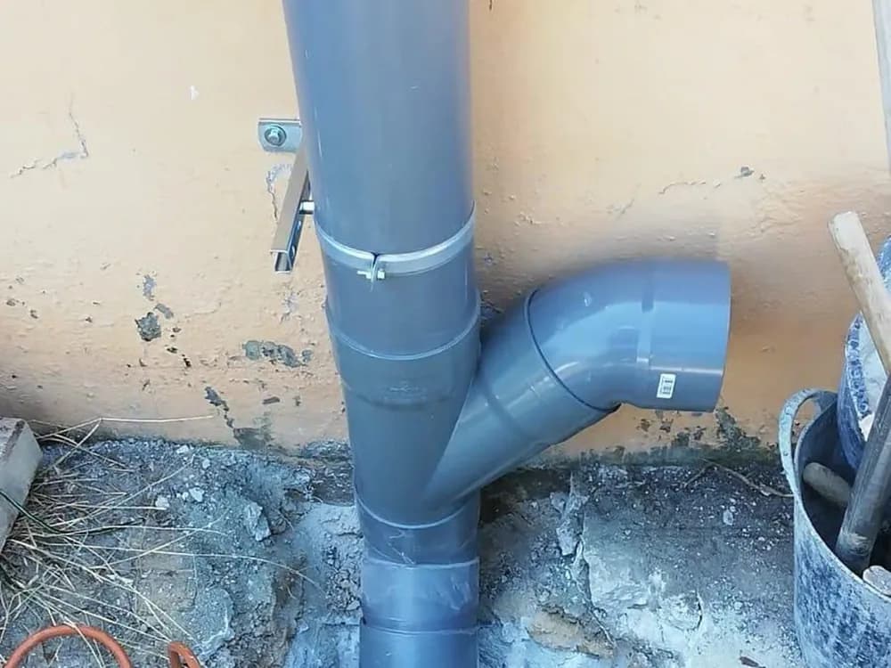Bajante nueva de PVC instalada en fachada y conectada bajo el pavimento